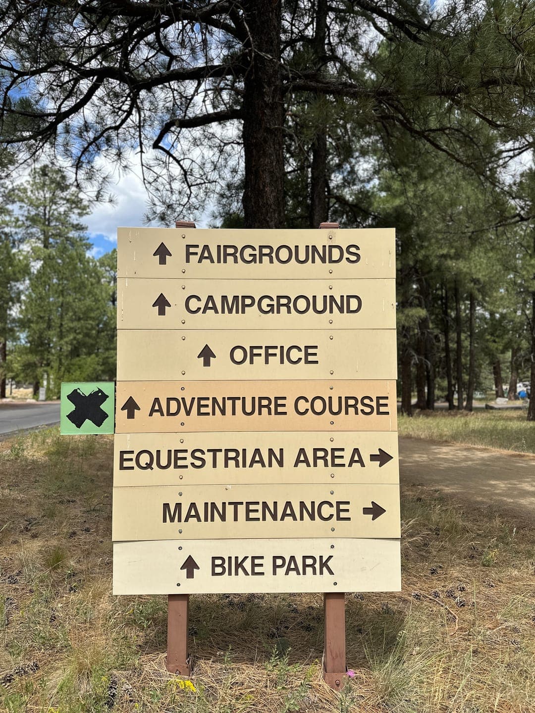 Wooden wayfinding sign at Fort Tuthill pointing the way to the fairgrounds, campground, office, and equestrian area